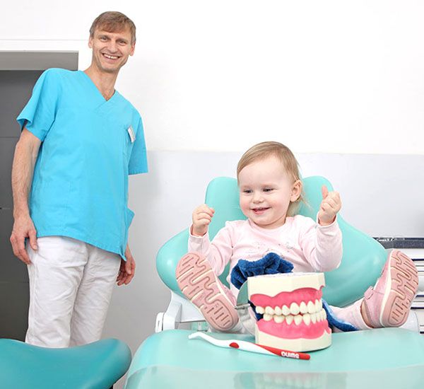 Dr. Mariusz Musiol erklärt einem Kind spielerisch das Gebiss anhand eines Models