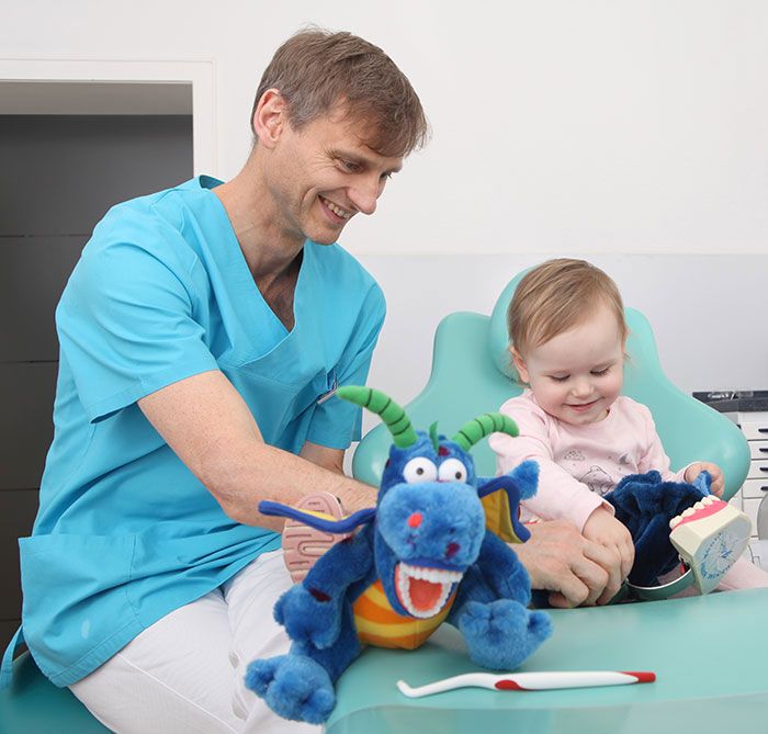 Dr. Mariusz Musiol erklärt einem Kind spielerisch das Gebiss anhand eines Models